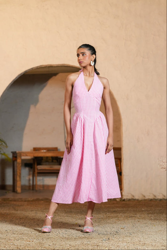 Woman in a pink dress standing in front of a beige wall with an archway.